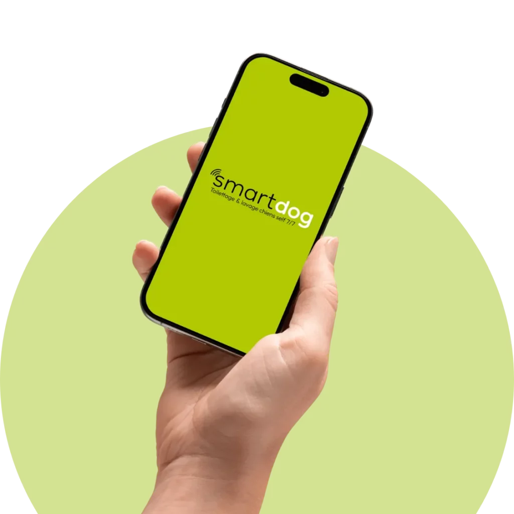 main qui tient un smartphone avec l'application smartdog lavage chien en libre service 7 jours sur 7 en fond